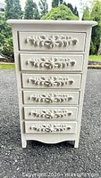 Front view showing six drawers with ornate appliques