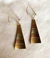 Front view of both trapezoid drop earrings on fabric background