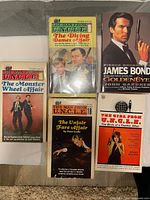 Five paperbacks including two Girl from U.N.C.L.E. titles, Monster Wheel Affair, Unfair Fare Affair, James Bond GoldenEye