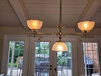 Fixture illuminated showing three lit frosted glass shades and brass bar