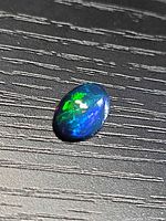 Top view of oval black opal showing multicoloured fire