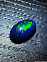 Top view of oval black opal showing green and blue play-of-color