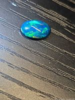 Top view of the oval black opal showing multicolour flashes