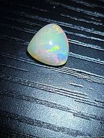 Trillion cabochon Ethiopian opal showing play-of-color on dark background