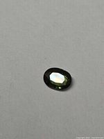 Front view of oval green sapphire showing table facet and overall color