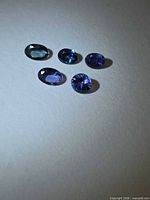 Five oval faceted gemstones on neutral background