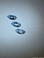 Three pear-cut light blue aquamarines on neutral background