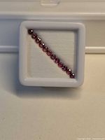 Row of round pink-orange sapphires in display case