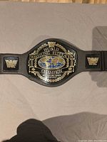 Full view of WWF toy championship belt laid flat showing central plate and side logos