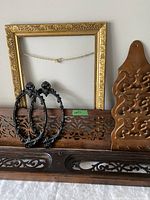 Group shot of all items: two fretwork panels, gilt frame, two black metal frames, wood letter holder