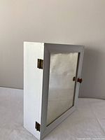 Side view of white wood mirrored cabinet showing hinges and knob