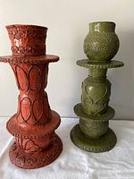 Front view of two paper mache candle holders, red and green