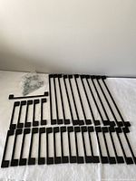 Array of black metal handles in three size groups laid out on surface with screws bag