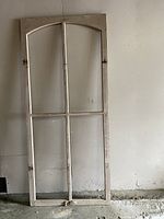 Full view of tall arched window frame leaning against wall