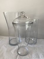 Three clear glass vases including lidded jar front view