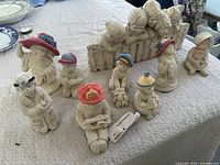 Group view of fence piece and seven freestanding child figurines on table