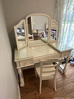 Vanity with attached tri-fold mirror and chair, angled view