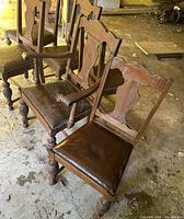 Front three-quarter view showing armchair and side chairs, wood frames and leather seats