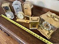 Group shot of all seven small mantel and desk clocks with tape for scale
