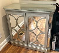 Front view of one mirrored console cabinet with circular overlay design
