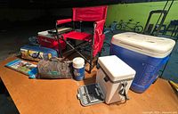 Group shot showing both Igloo coolers, red folding chair, Broadstone tent bag, skittles bag, wine tote cooler open displaying cutlery