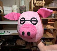 Front view of plush pink pig head with glasses detail