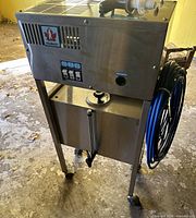 Full view of distiller on stand, showing stainless construction, casters, reservoir and hose