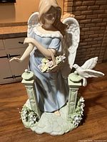 Front view of porcelain angel figurine with columns, flowers and dove