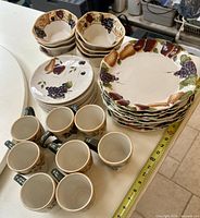 Stacked dinner plates, salad plates, bowls and mugs laid out with tape measure