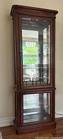 Full front view of mahogany curio cabinet showing glass panels, mirrored back and two-section doors