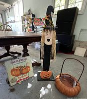 Group shot of witch figure, pumpkin sign and basket