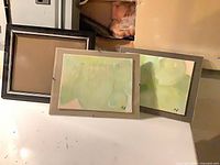 All three pieces–two framed paintings and one empty frame–grouped together