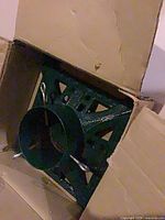 Stand inside box showing green cast iron base and tightening bolts