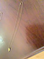 Full view of gold-tone leaf pendant necklace hanging to show total length