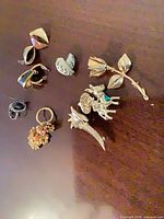 Overall view of all ten jewellery pieces laid out on dark surface