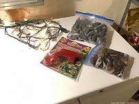 String lights, packaged repair tool, two bags stones on white surface