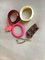 All jewelry pieces laid out: three resin bangles, beaded stretch bracelet, chain bracelet with charm, palm tree brooch