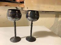 Two tarnished silverplate goblets with rope stems on table