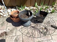 Group shot of two terracotta pots, grey pedestal urn, black square planter, two wire hanging basket frames on patio