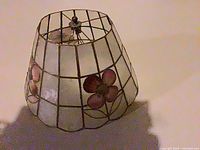 Side view of stained glass lampshade showing grid pattern, pink flower inlay and tapered shape