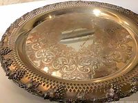 Oblique view showing engraved center, pierced rim, grape motifs, tarnish