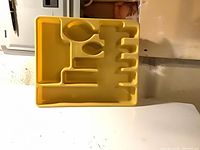 Front view of yellow plastic cutlery tray showing compartment layout