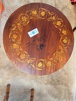 Top view showing round shape, floral marquetry border and black stains