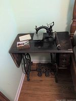 Overall view of treadle sewing machine, cabinet, drawers, and accessory box