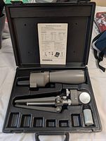 Scope, tripod, lens caps, accessory vial and instruction sheet arranged in molded carry case