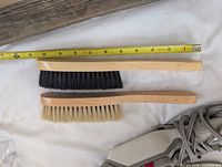 Two wooden-handled soft utility brushes, measuring tape and partial Rowenta cord visible