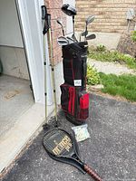 Group shot of golf bag with clubs, hiking poles, tennis racket, bag of balls and tees
