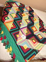 Folded quilt showing Log Cabin pattern, green border, prairie points