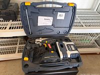 Open carrying case showing drill, battery charger, manual and accessories