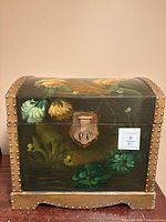 Front view showing painted floral design, dome lid, metal stud trim